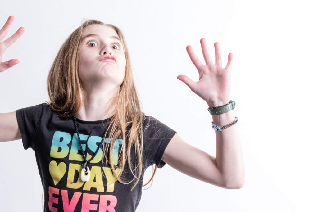 Young girl making a funny face with hands in the air